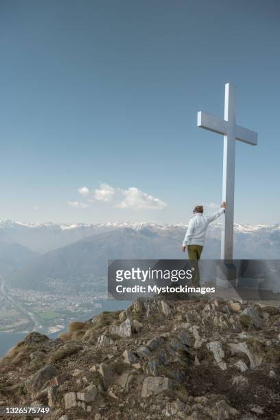 männlicher wanderer betrachtet die aussicht von der bergspitze - cross shape stock-fotos und bilder