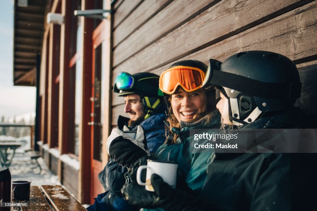 Happy male and female friends spending leisure time while having coffee at ski resort