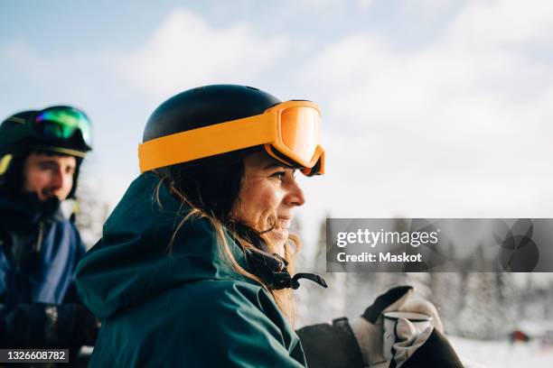 smiling woman wearing ski goggles while holding coffee cup during winter - ski resort fotografías e imágenes de stock