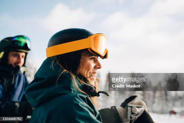 smiling woman wearing ski goggles while holding coffee cup during winter - sport d'hiver photos et images de collection
