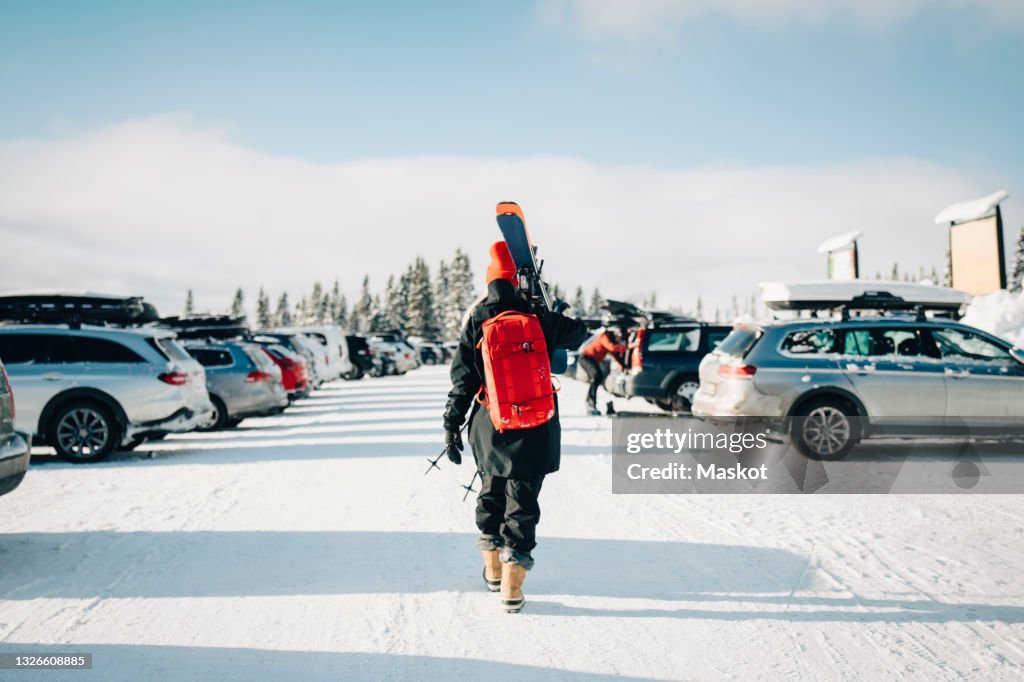 Rear view of woman walking at parking lot during winter