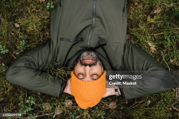 directly above shot of man lying down on land in forest - green hat fotografías e imágenes de stock