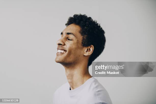 side view of happy young man with eyes closed against white background - man closed eyes stock-fotos und bilder