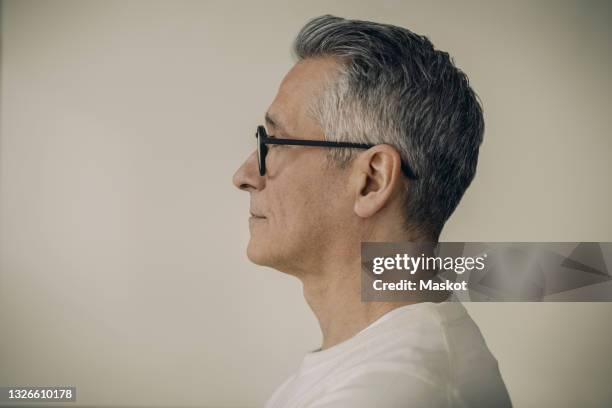 profile view of mature man wearing eyeglasses against beige background - profilo vista laterale foto e immagini stock