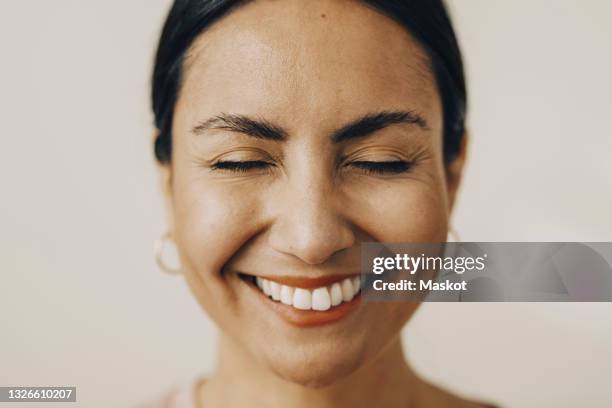 cheerful mid adult woman with eyes closed against white background - mindfulness stockfoto's en -beelden