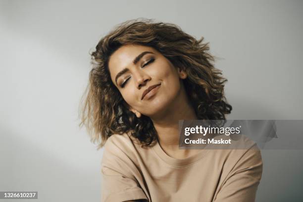 smiling woman with eyes closed against white background - hoofd schuin stockfoto's en -beelden