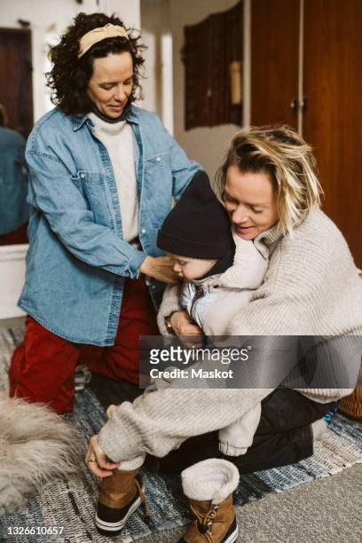 lesbian mothers getting daughter dressed at home - västra götaland county stock-fotos und bilder