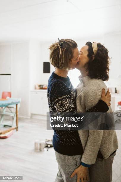 affectionate lesbian couple kissing each other at home - photos of lesbians kissing stock pictures, royalty-free photos & images
