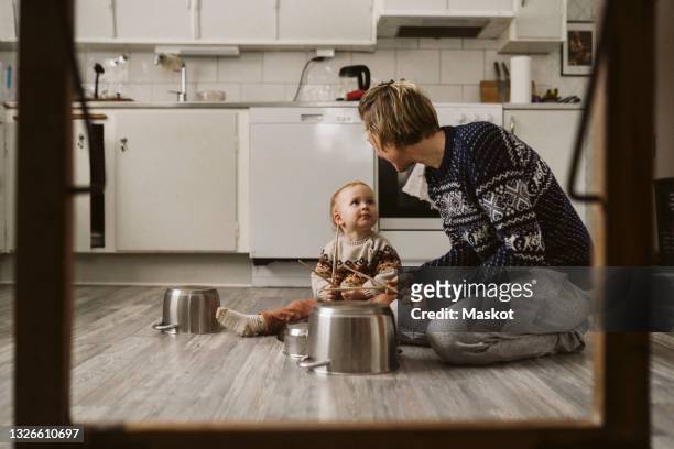 girl looking at mother while playing utensils with chopsticks in kitchen at home - västra götaland county stock pictures, royalty-free photos & images