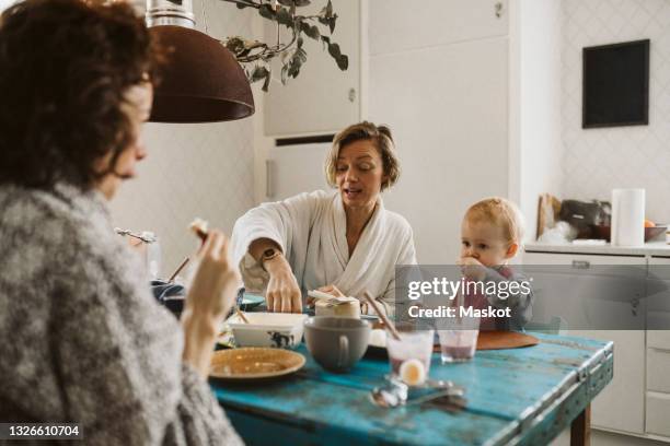 woman talking with girlfriend while having breakfast at home - lesbian mom stock pictures, royalty-free photos & images