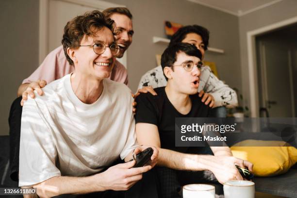 happy male friends playing video game at home - manly room stock-fotos und bilder