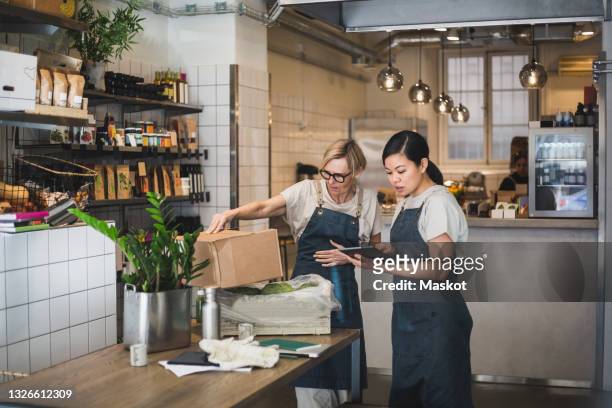 female entrepreneurs discussing over digital tablet in store - small business stock pictures, royalty-free photos & images
