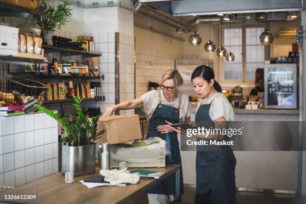 female entrepreneurs discussing over digital tablet in store - small business imagens e fotografias de stock