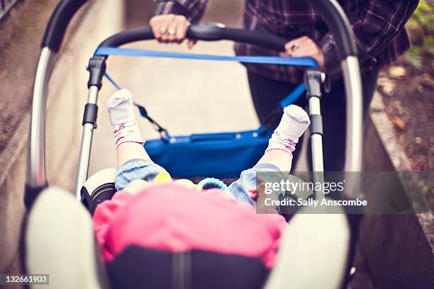 mother pushing baby in pram - mum pushing pram stock-fotos und bilder