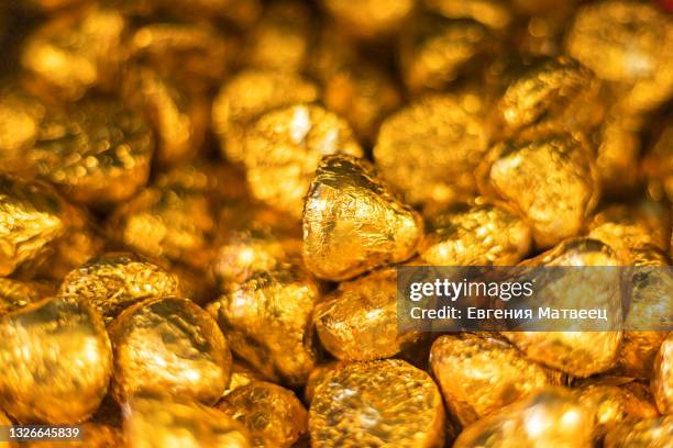 chocolate candies wrapped in golden metal foil heap on shop shelf. confectionery concept. close up - chocolate foil stock-fotos und bilder