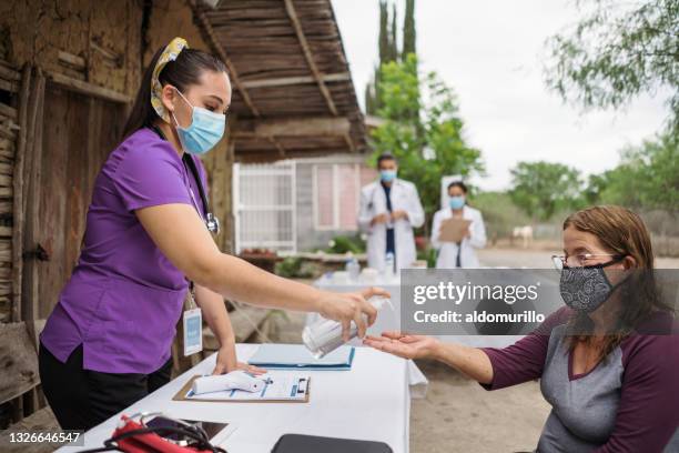 health care worker putting antibacterial gel on patient's hand - brigade stock pictures, royalty-free photos & images