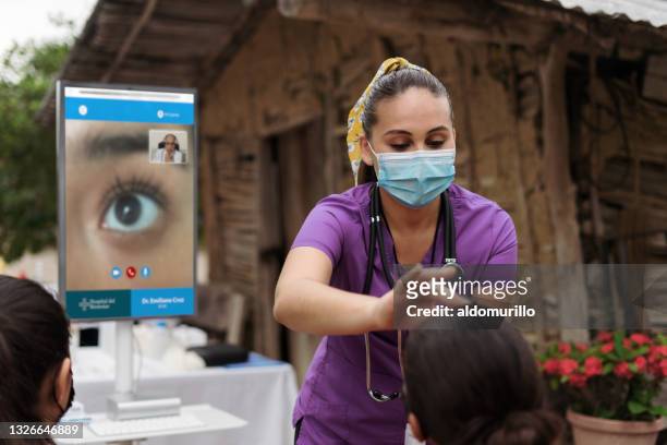 latin nurse with wireless device checking patient's eye - brigada imagens e fotografias de stock