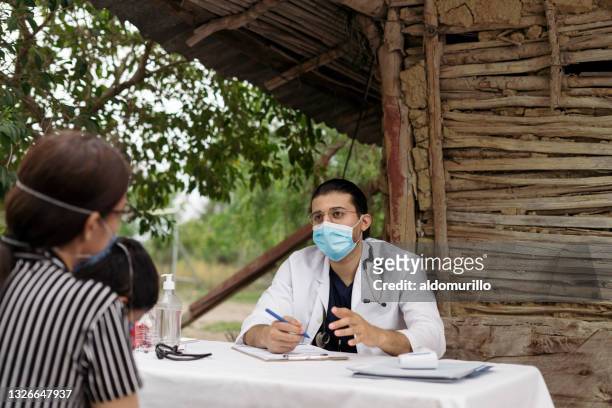 médico masculino hablando con pacientes en el área rural - brigades fotografías e imágenes de stock