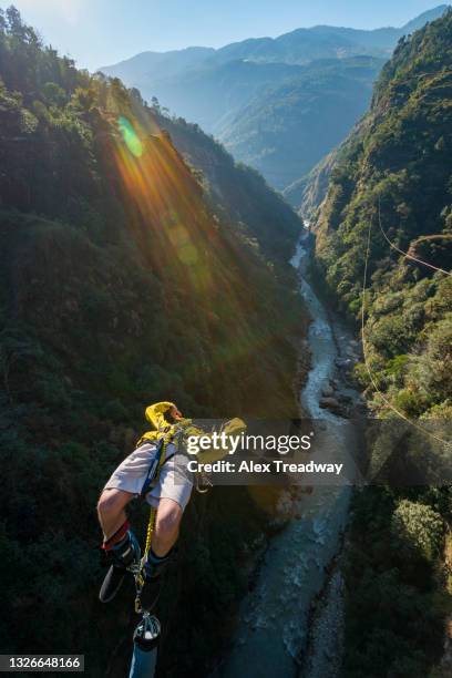 a man jumps a canyon swing from a bridge over the bhote kosi river in nepal - bungee jump stockfoto's en -beelden