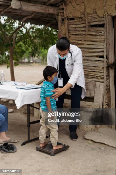 male doctor putting little boy on scale - brigada imagens e fotografias de stock