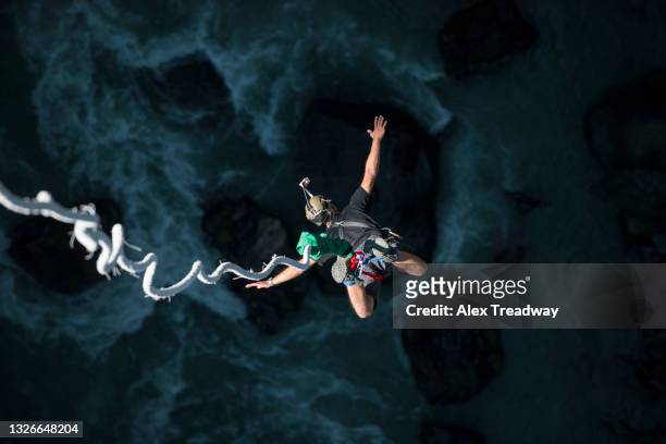 a man bungee jumps from a bridge spanning a gorge in nepal - bungee jump - fotografias e filmes do acervo