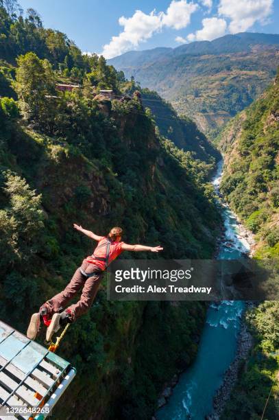 a girl bungee jumps from a bridge spanning a gorge in nepal - bungee jump stockfoto's en -beelden