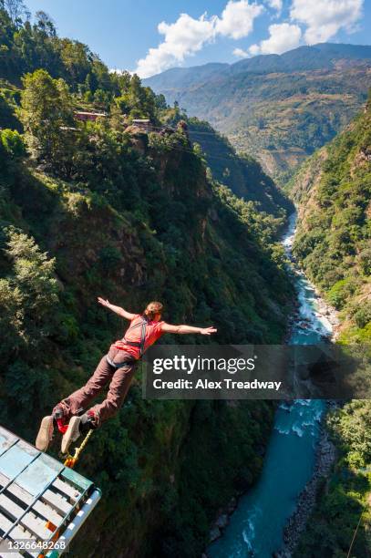 a girl bungee jumps from a bridge spanning a gorge in nepal - bungee jumping stock pictures, royalty-free photos & images