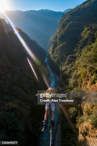 a man jumps a canyon swing from a bridge over the bhote kosi river in nepal - bungee jump stockfoto's en -beelden