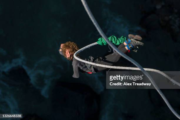 a girl bungee jumps from a bridge spanning a gorge in nepal - bungee cord stock pictures, royalty-free photos & images