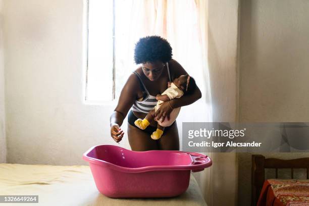 mother checking water temperature - african american woman bath stock pictures, royalty-free photos & images