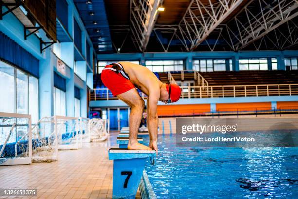 man preparing for a jump in an indoor pool - starting block stock pictures, royalty-free photos & images