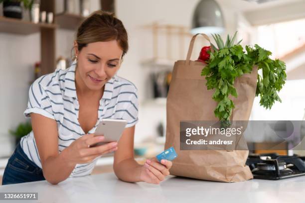 donna a casa che paga online per una consegna di cibo con carta di credito - online shopping foto e immagini stock