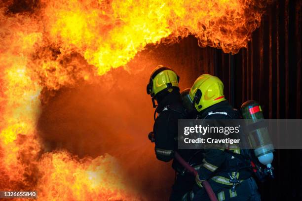 fire fighter fighting with fire holding extinguishing water fire hose .they are fighting with fire by use the water. - oxygen cylinder stock pictures, royalty-free photos & images