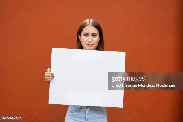 young latino woman holding a blank sign - placard stock pictures, royalty-free photos & images
