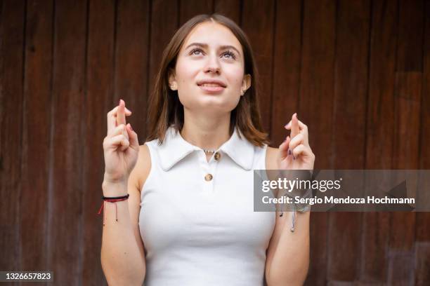 young mexican woman looking up and crossing her fingers in hope, wishing - acaso imagens e fotografias de stock