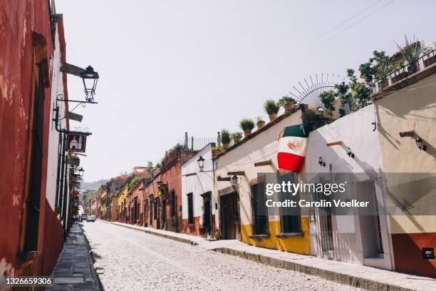 mexican flag flying from a house on a residential street in san miguel de allende - colonial flag stock pictures, royalty-free photos & images