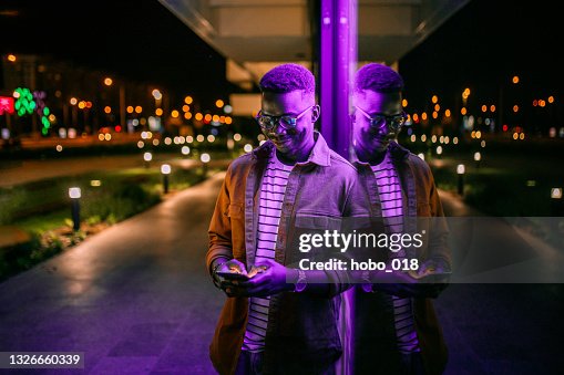 Using Phone in a front of neon lights on the street Using Phone in a front of neon lights on the street