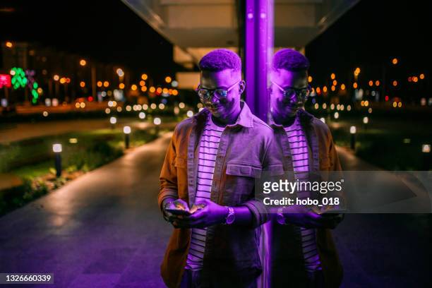 using phone in a front of neon lights on the street - night stock pictures, royalty-free photos & images