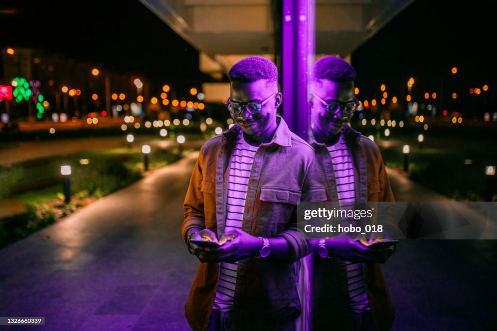 Using Phone in a front of neon lights on the street