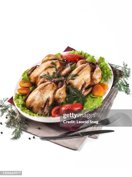 food photography of festive baked whole baby chickens side view with tomato and dried apricots served on a white background isolated close up - hoofdgerecht stockfoto's en -beelden