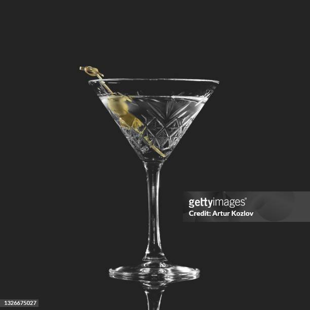 alcoholic drink. crystal goblet with alcohol and olive isolated on black background - martini bildbanksfoton och bilder