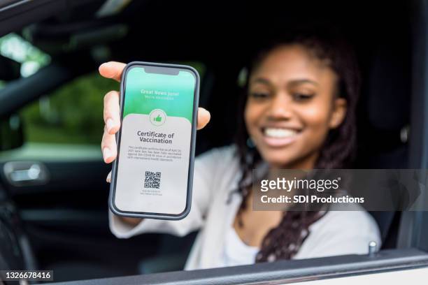 woman shows digital vaccination certificate - mobile app car stock pictures, royalty-free photos & images