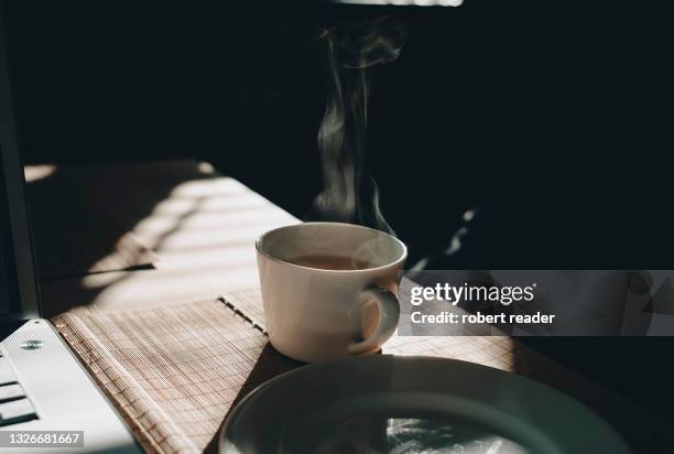 steaming cup of tea on table - ティーカップ ストックフォトと画像