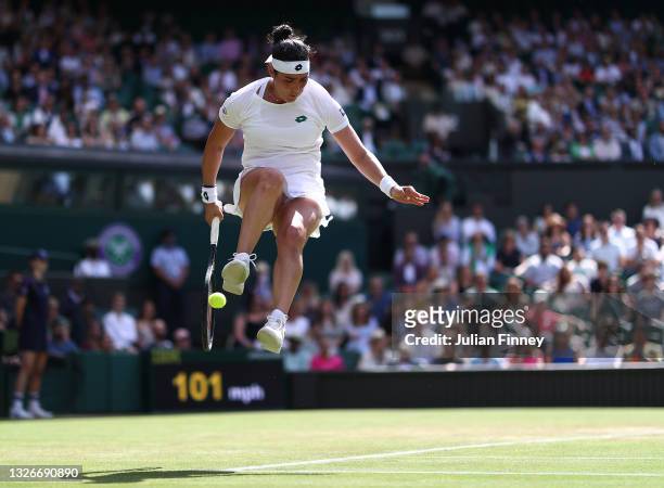 Ons Jabeur of Tunisia jumps in the air as she plays a forehand behind her back during her Ladies Singles Third Round match against Garbine Muguruza...