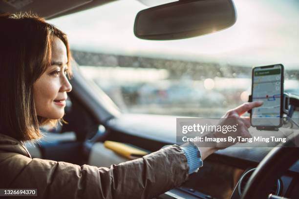 young pretty asian woman using gps navigation in the car - sistema de posicionamiento global fotografías e imágenes de stock