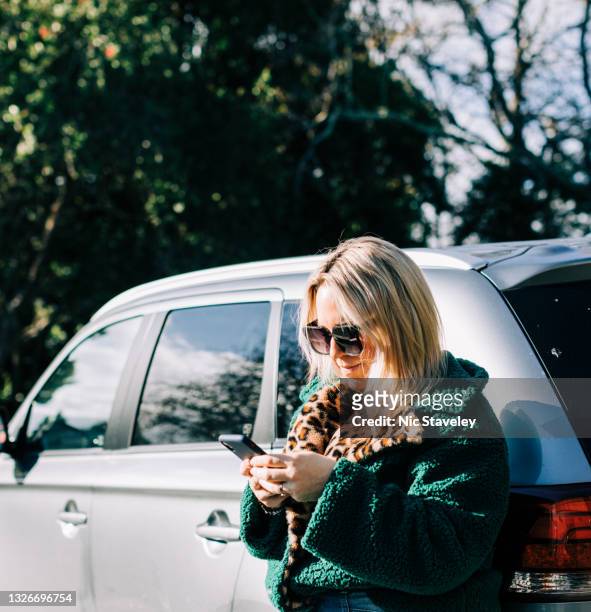 woman standing beside car holding mobile phone - calling on the side road stock pictures, royalty-free photos & images