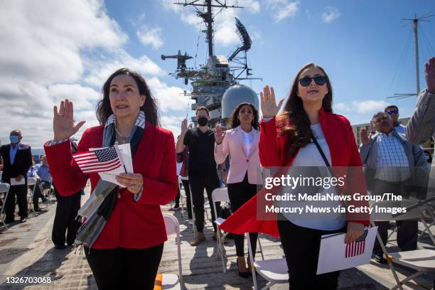 Maria Laura Limpias Chavez, left, of Bolivia, Sahara Loffsner, of Colombia, and fellow new American citizens, take the Oath of Allegiance led by U.S....