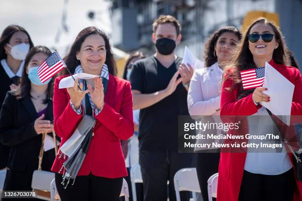 Maria Laura Limpias Chavez, left, of Bolivia, Sahara Loffsner, of Colombia, and fellow new American citizens, applaud after taking the Oath of...