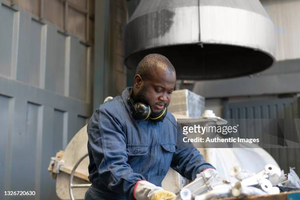afro-american worker handling metallic parts at metallurgical factory - material handling stock pictures, royalty-free photos & images