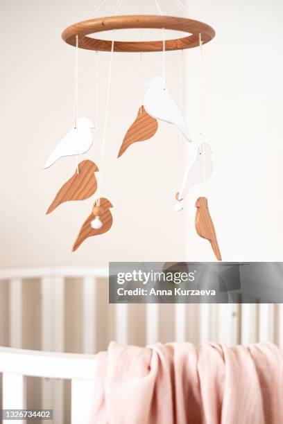 close up view of baby room with a white baby bed and a baby mobile hanging over the bed, selective focus. nursery interior. - baby mobile stock pictures, royalty-free photos & images